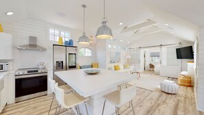 Une cuisine moderne avec des meubles blancs, des appareils en acier inoxydable et un îlot central doté de sièges.