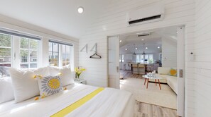 Ein modernes Schlafzimmer mit einem großen Bett, Blick auf die Küche und einer Pendelleuchte.