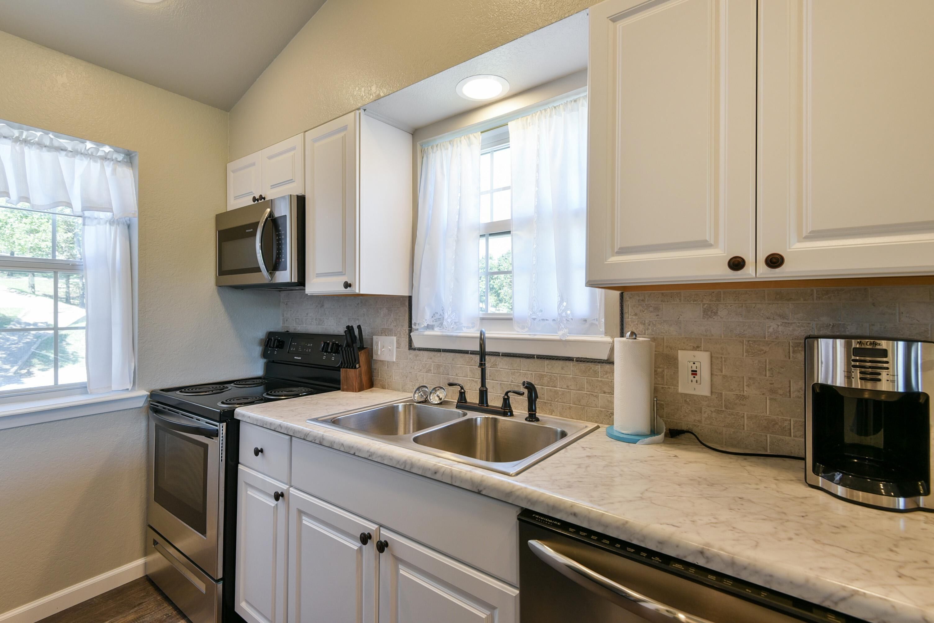 A kitchen with white cabinets, stainless steel appliances, a double sink, and a coffee maker.