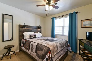 A bedroom with a bed, a ceiling fan, a window with curtains, a desk, and a television. - Suite Outlook Penthouse near Downtown (Branson)