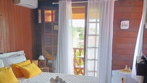 Una habitación acogedora con una cama, una mesita, un refrigerador y una ventana con cortinas.