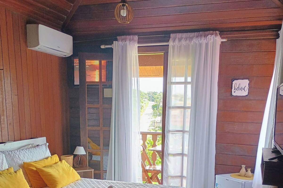 Ein gemütliches Zimmer mit einem Bett, einem kleinen Tisch, einem Kühlschrank und einem Fenster mit Vorhängen.