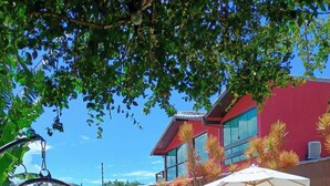 Una piscina con una hamaca colgante y sillas de descanso, rodeada por un edificio rojo y vegetación.