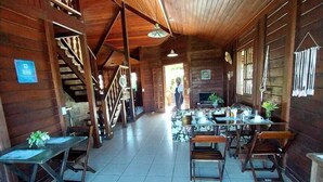 Un interior de madera con una escalera, mesas y sillas dispuestas para comer.