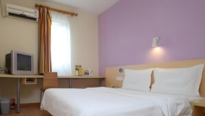 A hotel room with a bed, a desk with a computer, a window with curtains, and an air conditioning unit. - 7 Days Inn Shenzhen Longhua Branch (Shenzhen)