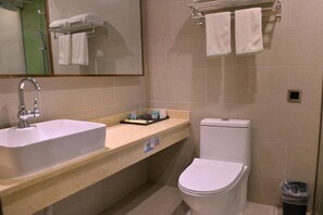 Un baño con lavamanos, inodoro y perchero para toallas.
