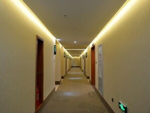 A hotel hallway with doors on both sides, emergency exit signs, and a carpeted floor. - Greentree Inn Luoyang Ruyang County Dujuan Avenue Hotel (Luoyang)