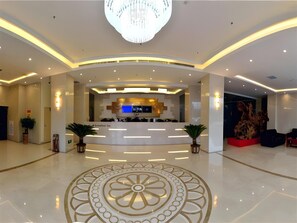 A modern hotel lobby with a central reception desk, a chandelier, and a decorative floor pattern. - Greentree Inn Luoyang Ruyang County Dujuan Avenue Hotel (Luoyang)