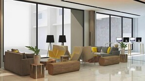A modern living room with a sofa, chairs, a coffee table, and a desk with computers. - Pollos Hotel & Gallery Rembang (Rembang)