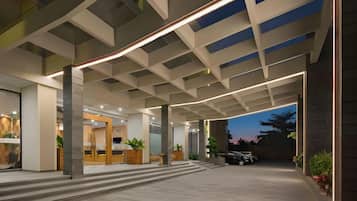 A modern hotel entrance with a spacious lobby, a reception desk, and a view of the sky.