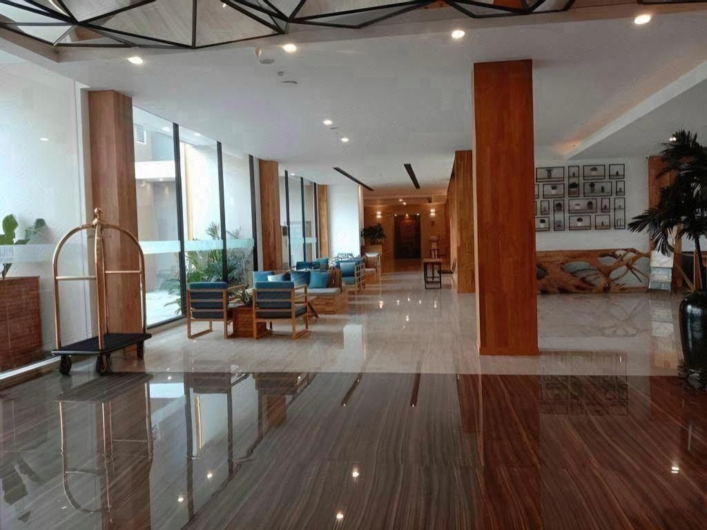 Um hall amplo com piso reluzente, área de estar e balcão de recepção.