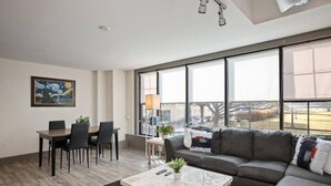 Una sala de estar moderna con comedor, ventanas amplias y un cuadro en la pared.