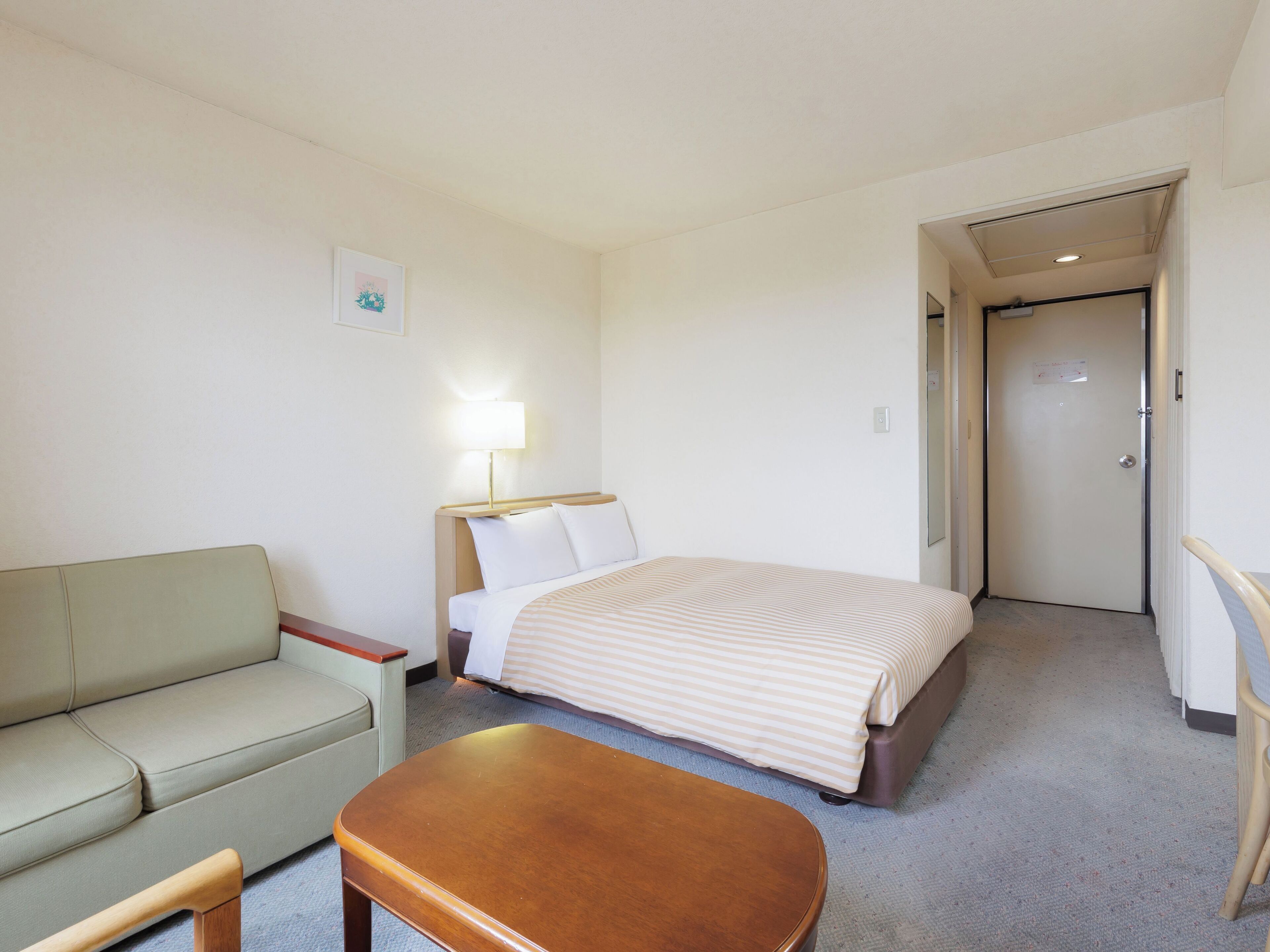 Una habitación de hotel con una cama, un sofá, una mesa y una lámpara.