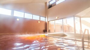 An indoor swimming pool with clear water, a ladder, and large windows allowing natural light. - FLEXSTAY INN Kashima Central (Kamisu)