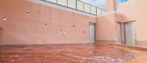 Un área de piscina interior amplia con vistas despejadas al cielo gracias a un techo de cristal, suelo de baldosas y techo alto con barandilla metálica.