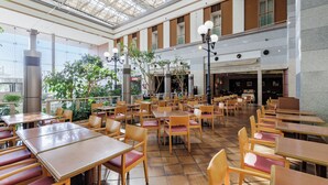 A spacious indoor dining area with multiple tables and chairs, a high ceiling with a glass roof, and a view of the outside through large windows. - FLEXSTAY INN Kashima Central (Kamisu)