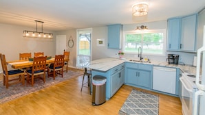 Een moderne keuken met blauwe kastjes, een marmeren aanrecht en een roestvrijstalen prullenbak.