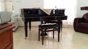A piano in a room with a white sofa and a brown armchair.