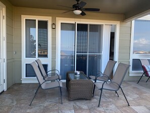 Relax in the comfort of this patio with a seating area featuring two chairs and a table, surrounded by large windows offering views of the surroundings.