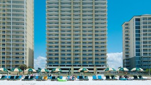 A high-rise hotel with multiple balconies, beachside lounge chairs, and umbrellas. - Twin Palms 1103 (Panama City Beach)