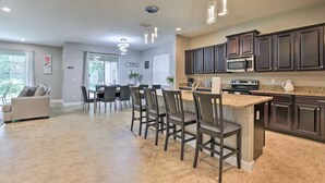 A spacious kitchen with dark cabinets, a central island, and a dining area with chairs and a table.