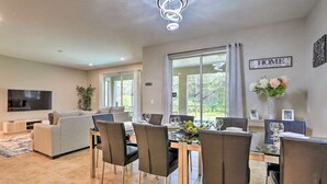 A modern living room with a sofa, TV, and dining area with chairs and a table.