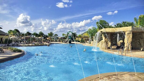 A large outdoor swimming pool with multiple water features, including a waterfall and water jets.