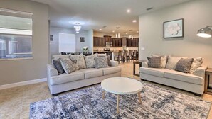 A spacious living room with a sofa set, a coffee table, and a dining area in the background.
