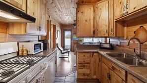 Una cocina con armarios de madera, estufa, microondas y pileta.