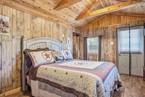 A wooden cabin-style bedroom with a bed, a window, and a door. - RRR Cabin on the Medina | 1800 Feet River | Deer (Medina)