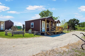 A small wooden cabin with a porch, a gravel driveway, and a picnic table. - RRR Cabin on the Medina | 1800 Feet River | Deer (Medina)