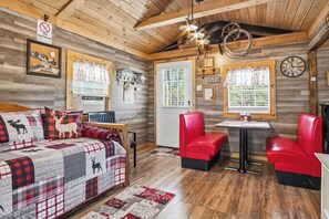 A cozy room with a bed, a table, and two red chairs.