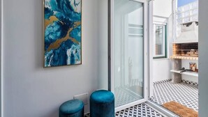 A modern bathroom with a glass shower door, a blue abstract painting, and a patterned floor. - Minty House (Setúbal)