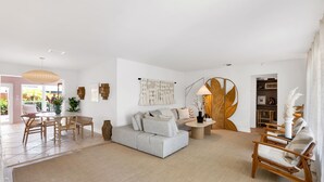 Uma sala de estar moderna com sofá, cadeiras, mesa de centro e área de refeições.