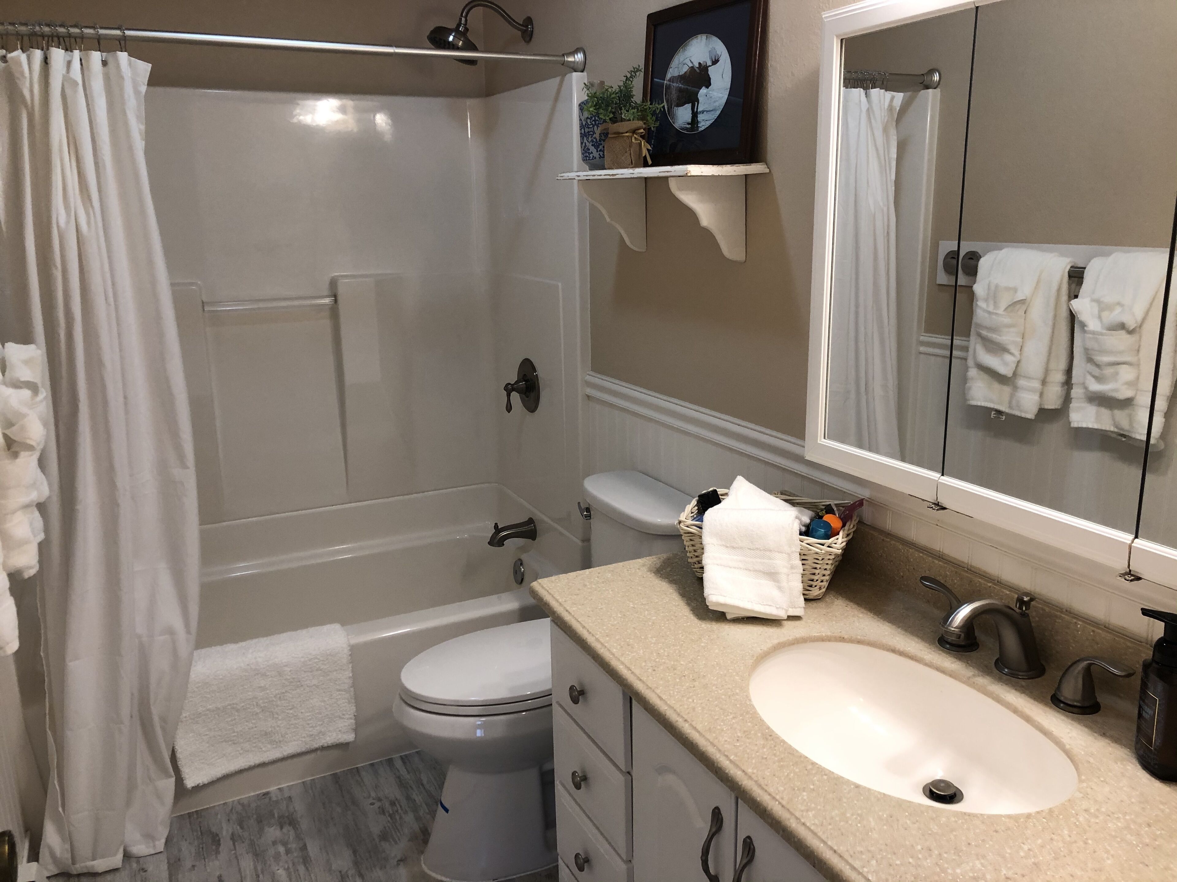 A bathroom with a bathtub, toilet, sink, and a mirror.