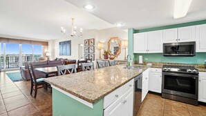A spacious kitchen with a granite countertop, stainless steel appliances, and white cabinets.