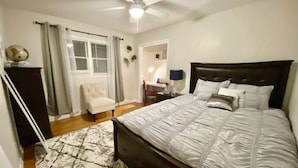 A bedroom with a bed, a chair, a desk, a ceiling fan, and a window with curtains. - Spacious & Cozy Unit in the Heart of Milwaukee (milwaukee)