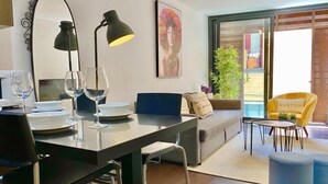 Ein modernes Wohnzimmer mit Essbereich, einer Couch, einem gelben Sessel und einem großen Fenster mit Aussicht.