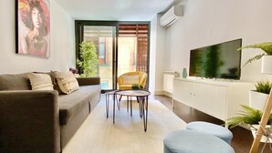 Ein modernes Wohnzimmer mit einer Couch, einem Couchtisch, einem Fernseher und einem kleinen Hocker.