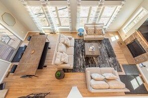 A spacious living area with a large wooden dining table, two sofas, a coffee table, and a fireplace.