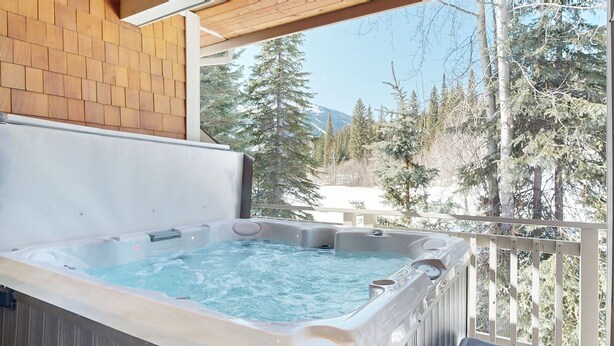 A hot tub with a wooden deck and a view of snow-covered trees and mountains. - Stunning Ski In/Ski Out Getaway-Outstanding Views (Sun Peaks)