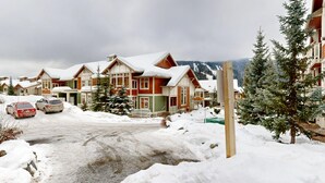 A snow-covered residential area with houses, a road, and a mountain in the background. - Stunning Ski In/Ski Out Getaway-Outstanding Views (Sun Peaks)