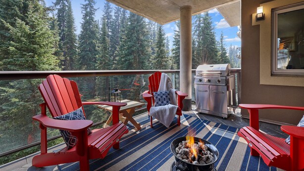 A balcony with red Adirondack chairs, a fire pit, and a grill. - Spacious Ski in/out Condo in Sun Peaks Village (Sun Peaks)