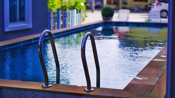 A swimming pool with metal handrails and a wooden deck edge. - Fahsai Hotel Aonang (Krabi)