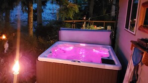 Un bain à remous doté d’une structure extérieure en bois et d’un couvercle transparent, entouré d’une terrasse avec une rambarde.