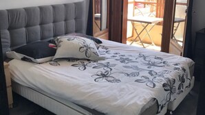 A bedroom with a bed, grey upholstered headboard, and a floral-patterned bedspread.