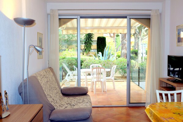 A living room with a sofa, a TV, and a dining area with chairs and a table.