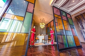 A lobby with a modern design, featuring a geometric patterned floor, a chandelier, and a table with chairs.