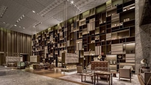 A spacious lobby with a large, well-lit bookshelf filled with books and decorative items, a marble floor, and comfortable seating areas. - Nanjing Golden Eagle International (Nanjing)