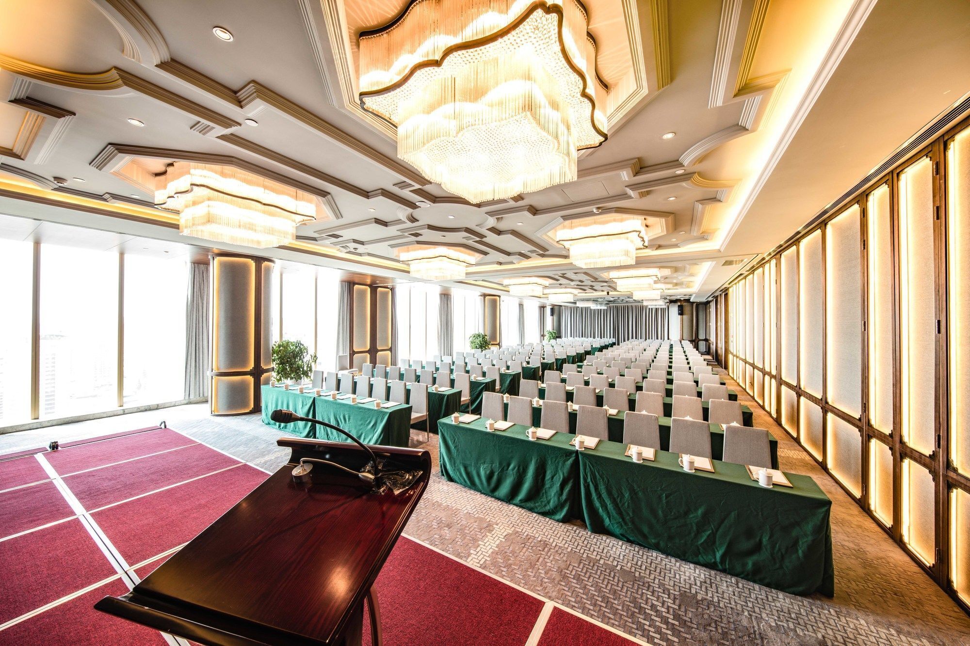 Une salle de conférence avec des rangées de tables, un grand lustre et de grandes fenêtres.
